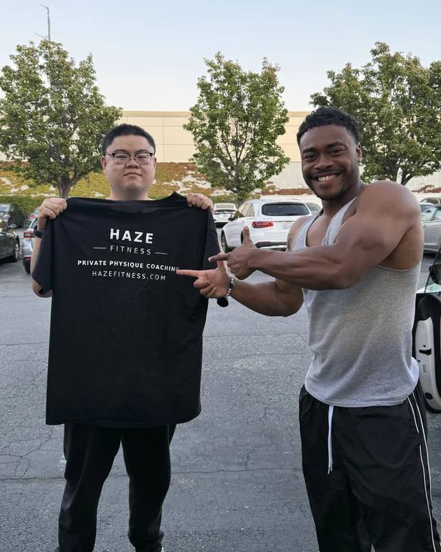 Andy and Zeke holding a Haze Fitness T-shirt outdoors after two months of coaching
