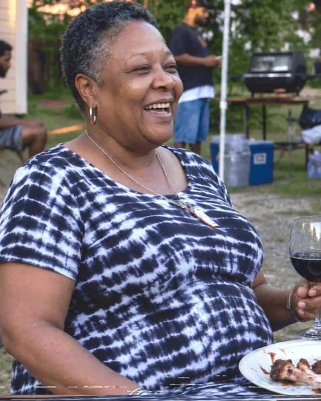 Denise smiling while seated at an outdoor gathering before beginning her fitness routine